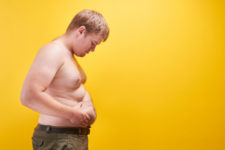 hombre con sobrepeso mirando su barriga.